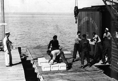 Black sailors unload ammunition at Port Chicago under the watch of a white officer.