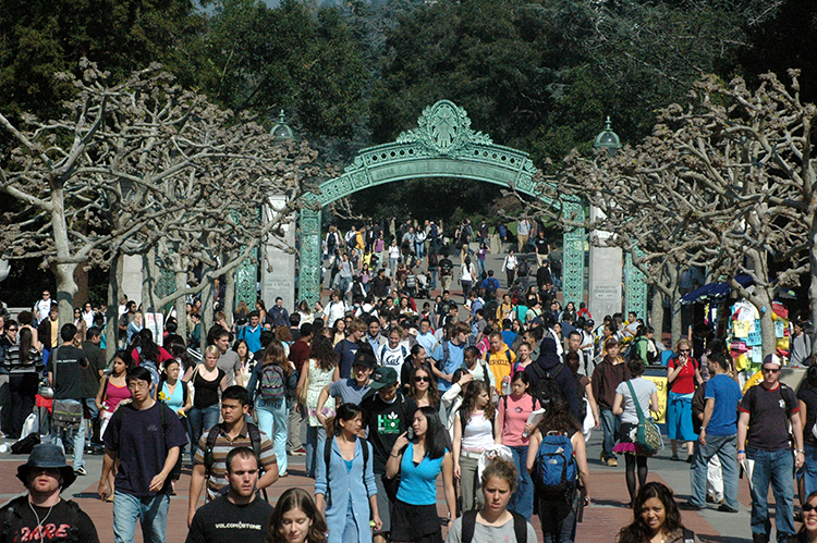 Students pass through Sproul Plaza with Sather Gate in the background