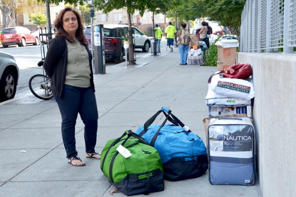 Woman waits with luggage.