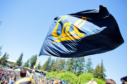 a student waves a Cal flag on a sunny day
