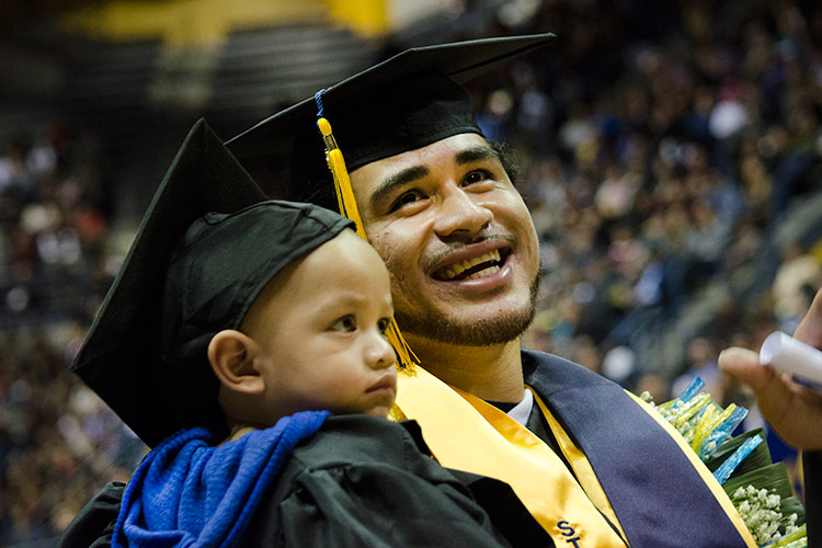 graduating football player with 10-month old son