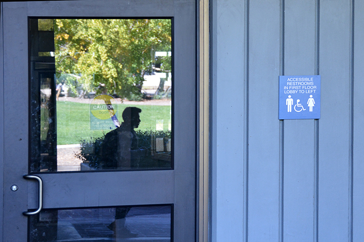 A sign outside of Evans Hall indicates that the restrooms are gender-neutral and ADA-compliant