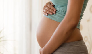 Pregnant's woman touching her belly with her hands.