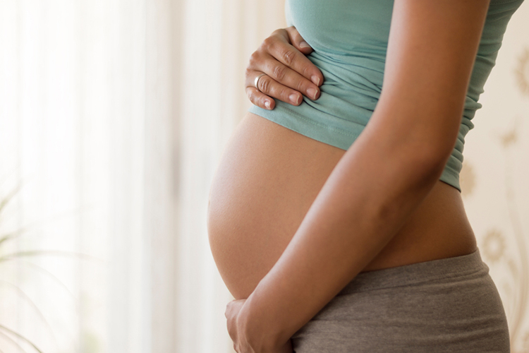 Pregnant's woman touching her belly with her hands.