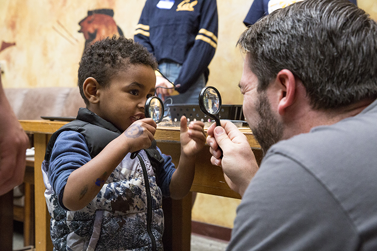 kid and adult holding magnifying glass