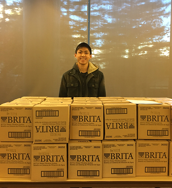 Student stands behind a stack of Brita boxes.