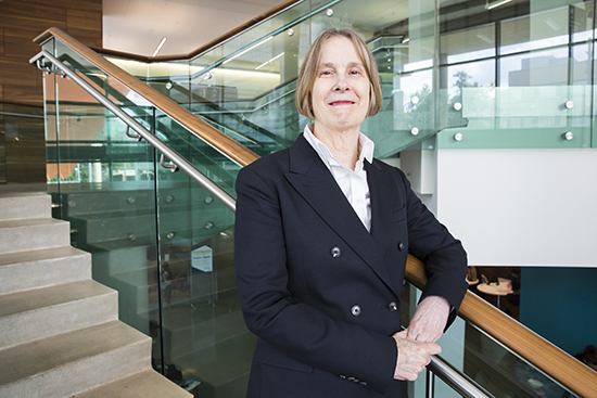 Portrait of Nancy Wallace standing by a glass staircase.