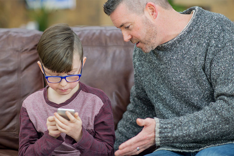 father and son on sofa with smartphone