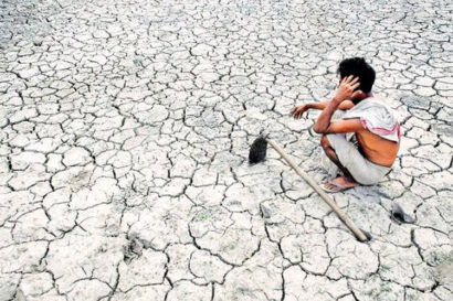 Man crouched on dry, cracked earth.