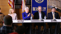 A photo of four people, including Carol Christ, sitting side by side at a conference panel table with the Berkeley logo behind them. A few audience members are seen in the bottom half of the photo. 