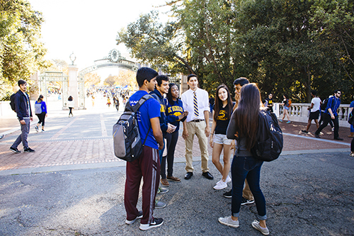 A group of students standing and talking near Sather Gate on the UC Berkeley campus.