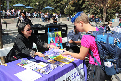 Student being handed a flyer at a table on Sproul Plaza.