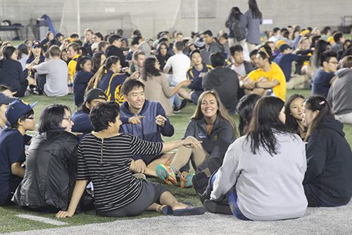 Groups of students sitting on a field during orientation leader training for GBO.