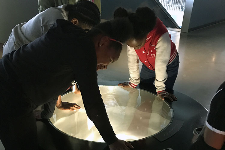 two girls peering into science exhibit