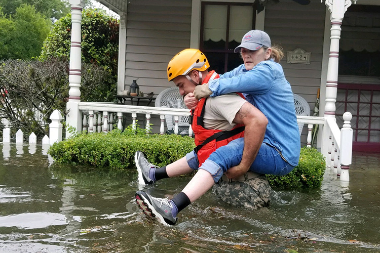 man carrying woman on back through flood