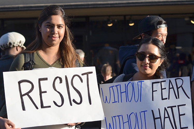 Two students expressing support for free speech rights by holding posters with "Resist" and "Without fear, without hate" written of them.