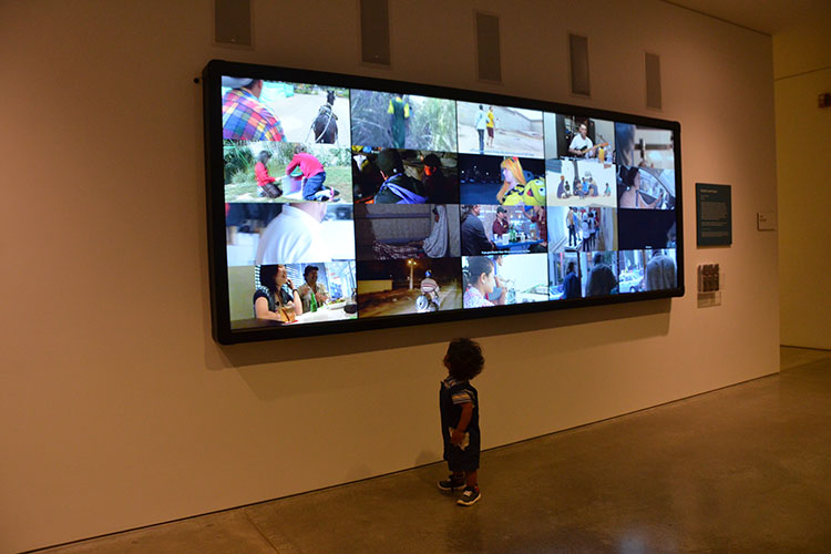 bank of videos at BAMPFA with small boy viewing