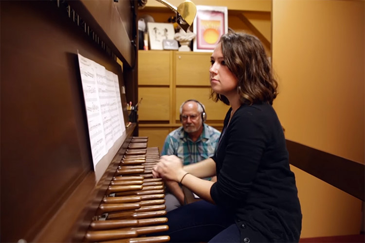 The University Carillonist, Jeff Davis, sits next to a student learning to play the carillon in the Campanile. They are in a practice room in his office, where no one can hear a student's musical mistakes outside of the room.