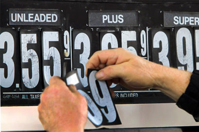 A man changes the numbers on a sign displaying gas costs. 