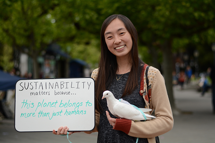 Student holding a sign in one hand and bird in another