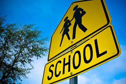 school sign with parent walking child