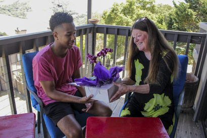 Cameron Rentie and Teryl Burt on Burt's balcony. Rentie is giving a Burt a purple orchid as a thank-you gift for hosting him last fall