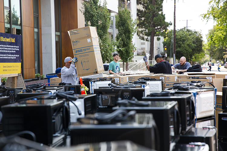 Crews work to unpacks rows of microwaves and mini-fridges in preparation for incoming students.