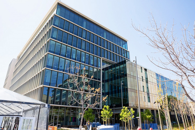 An eight-story glass building, adorned with freshly planted trees on the corner of Shattuck and Hearst Avenues