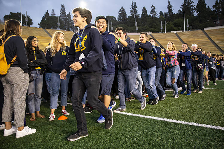 new students do a conga line, laughing and smiling