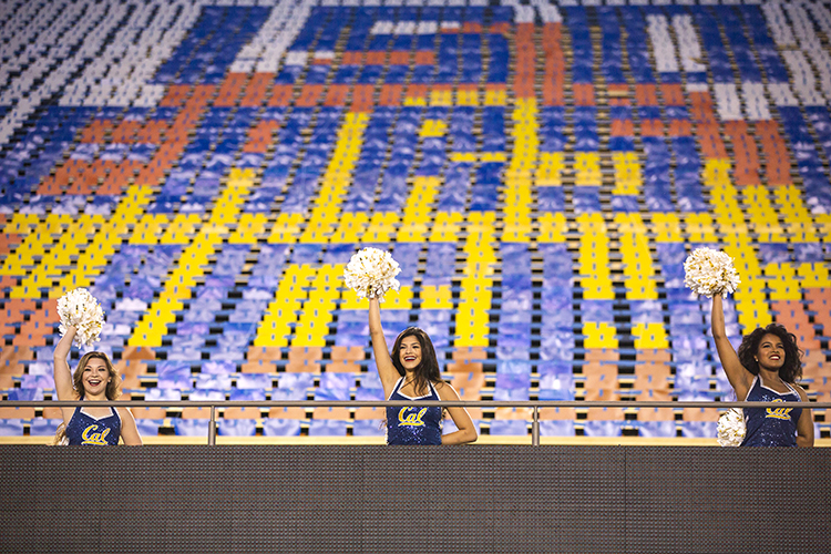 three dance team members hold their pompoms for the crowd