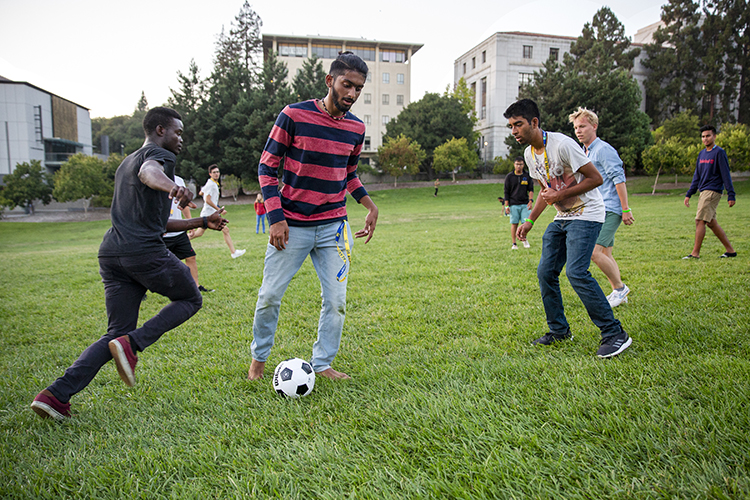 new student plays soccer with friends