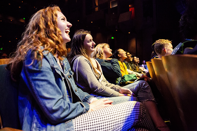 students laugh while watching standup comedy in zellerbach hall