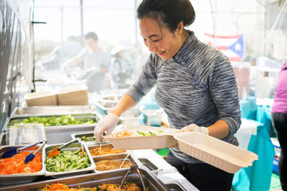 Han Truong loads up a to-go container with noodles and vegetables for customers of her restaurant