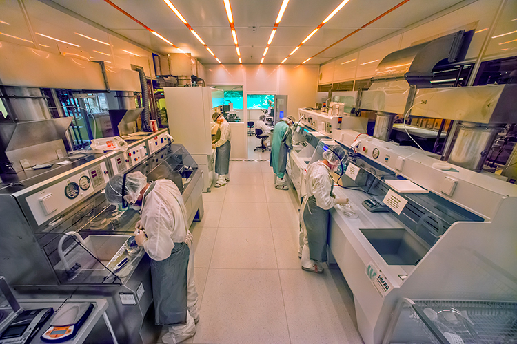 Scientists in white jumpsuits work in a clean room