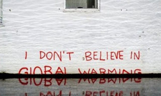 Graffiti on a wall in a flooded street that reads "I don't believe in global warming."