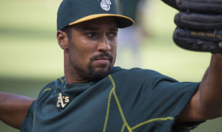 A photo of Marcus Semien in his baseball uniform about to throw a ball with a focused look on his face. 