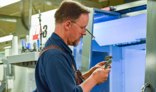 A photo of Gordon Long looking at a tool inside a laboratory.