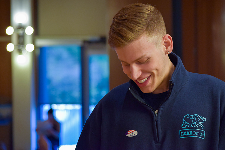 A student in blue looks at his i voted sticker