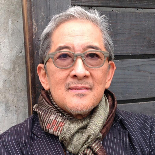 headshot of a person with short salt-and-pepper hair, tinted glasses and a scarf with a neutral look on his face