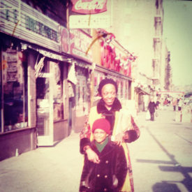 Quame at age 7 standing with his mom on a city street in New York