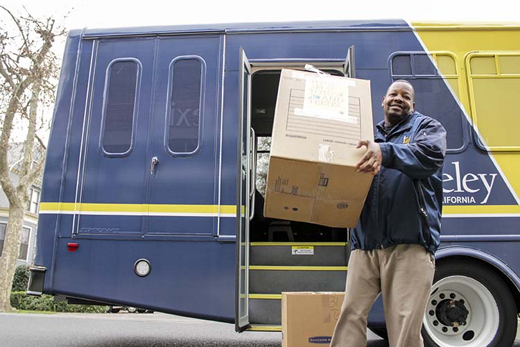 a man holds a box in front of a bus