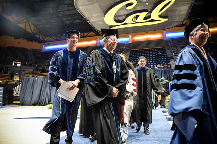 a group of people in gowns walk off stage