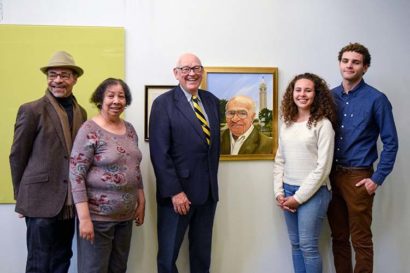 Five people stand in front of a portrait