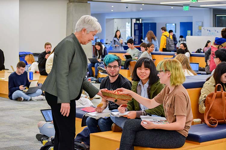 A woman gives cookies to students