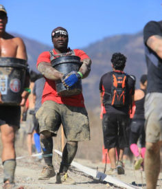 Marco carrying a bucket of rocks not looking happy