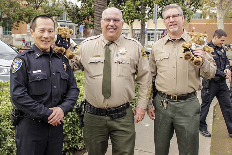 three men pose with bear stuffed animals