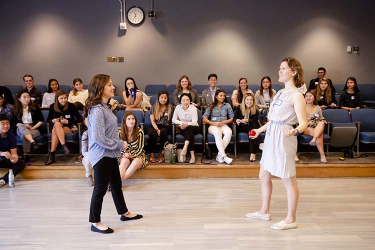 two women talk in front of a crowd