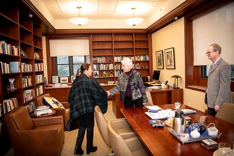 a woman shakes the hand of another woman in an office