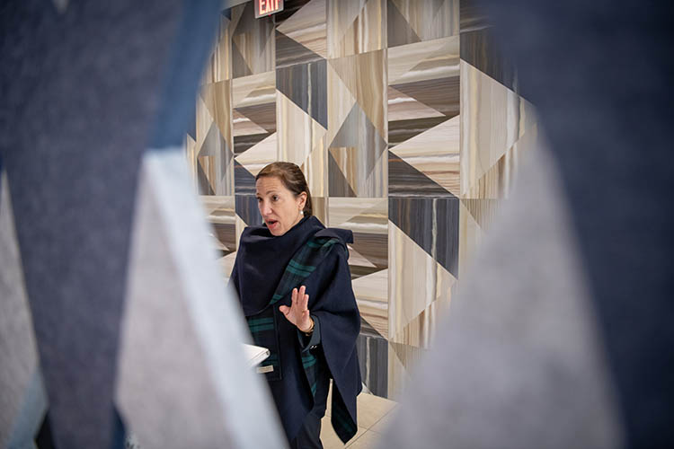 a woman talks in front of an interesting background