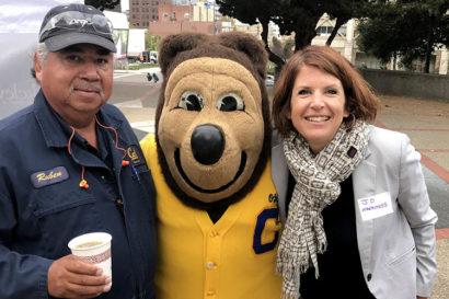 a woman stands with a man and Oski character